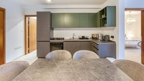 A modern kitchen with green cabinets, a dining table with four chairs, and a visible stove.