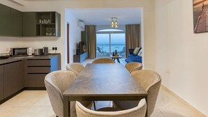 A modern kitchen with a dining area, a view of the sea, and a balcony with a table and chairs.