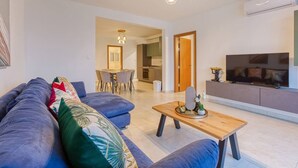 A modern living room with a sofa, a wooden coffee table, and a TV.
