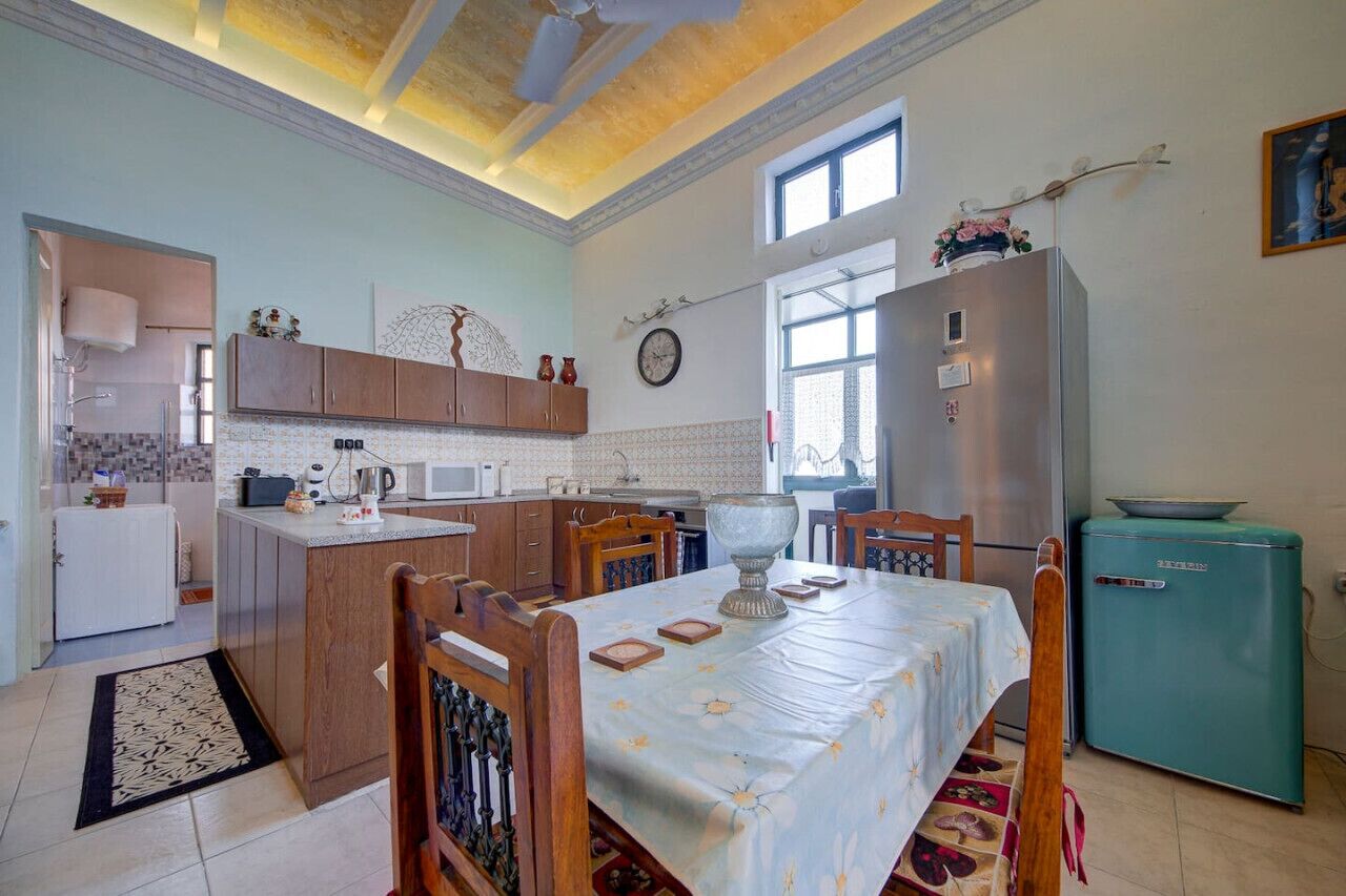 A compact kitchen with wooden cabinets, a dining table, and a teal refrigerator.