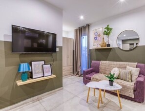 A modern living room with a flat-screen TV, a sofa, a coffee table, and a small plant.