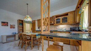 A kitchen with wooden cabinets, a granite countertop, and a dining area with wooden chairs. - Traditional Maltese Escape with Rooftop Terrace! (Ħad-Dingli)