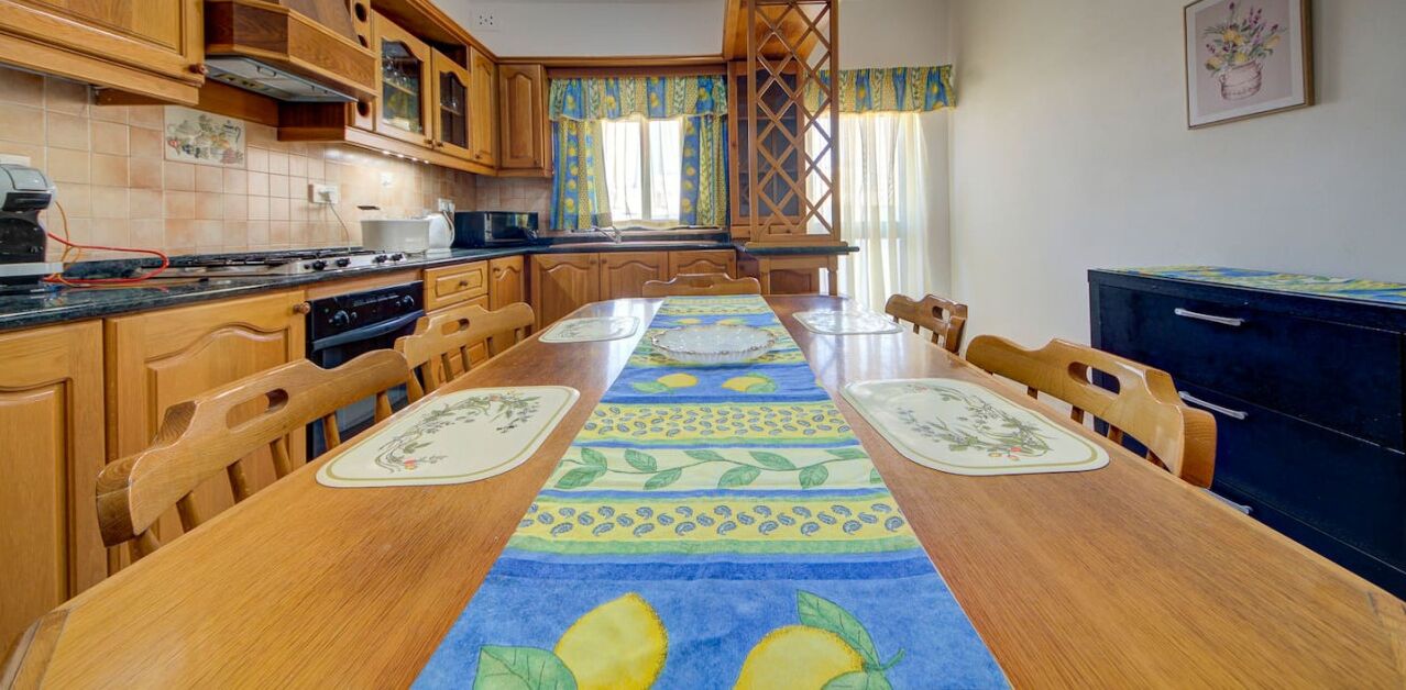 A kitchen with wooden cabinets, a stove, and a dining table with a table runner.