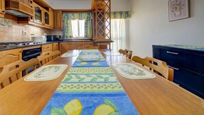 A kitchen with wooden cabinets, a stove, and a dining table with a table runner. - Traditional Maltese Escape with Rooftop Terrace! (Ħad-Dingli)