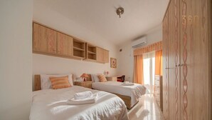 A hotel room with two beds, a wooden wardrobe, and a window with curtains. - Traditional Maltese Escape with Rooftop Terrace! (Ħad-Dingli)