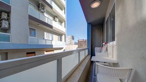 A balcony with a white chair and table, a railing, and a view of other buildings. - Modern 3BR home with Balcony in Central Msida (L-Imsida)