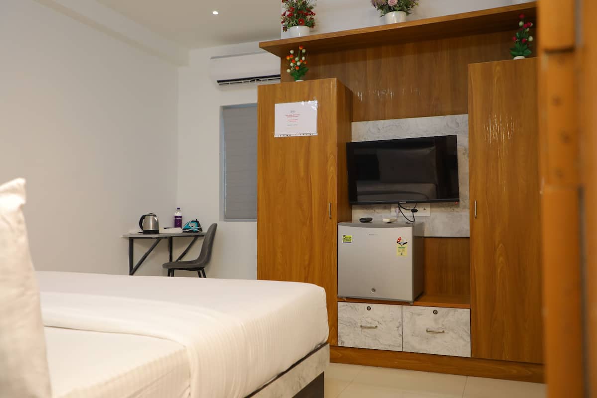 Une chambre à coucher comprenant un lit, un bureau avec une chaise, une télévision et un réfrigérateur.