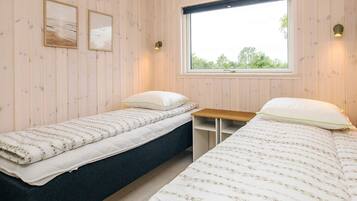 Een kamer met twee bedden, een raam en twee aan de muur bevestigde fotolijstjes.