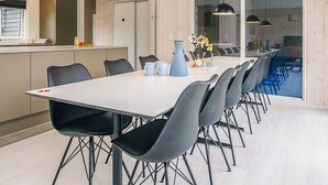 Ein moderner Essbereich mit einem langen Tisch, schwarzen Stühlen und Pendelleuchten.