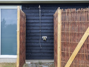 A black wooden wall with a metal pipe and a control box.