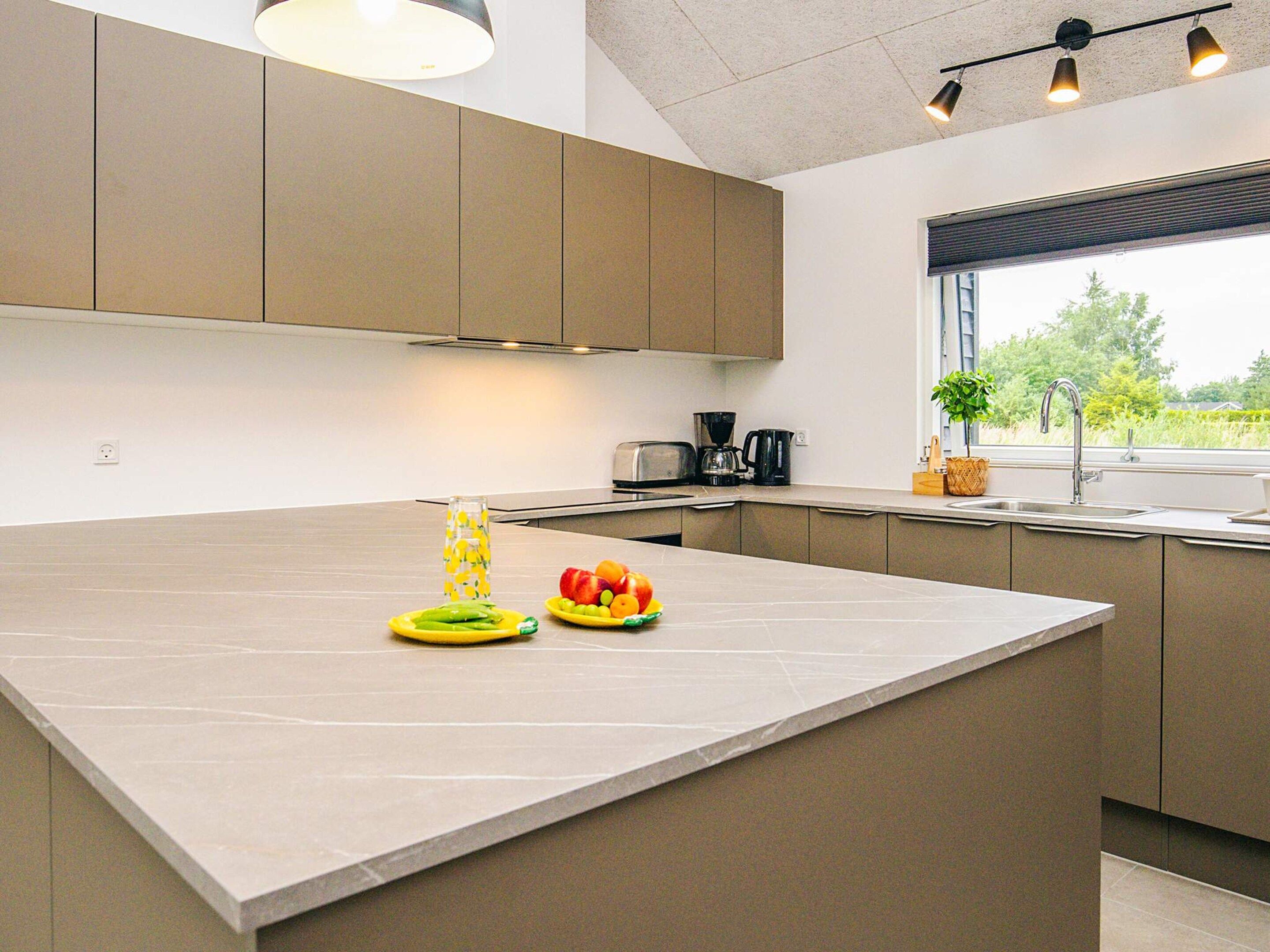Een moderne keuken met een groot eiland, inbouwapparatuur en uitzicht op groen.