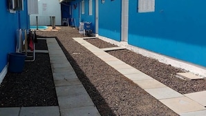 A narrow pathway flanked by blue buildings with a small pool area and a water tank on the roof. - Pousada Água Azul (Capao da Canoa)