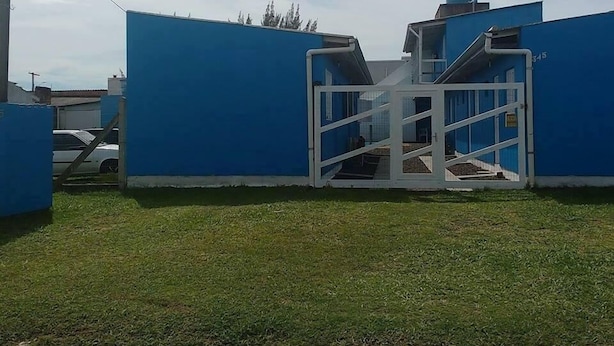A blue industrial building with a white metal gate. - Pousada Água Azul (Capao da Canoa)