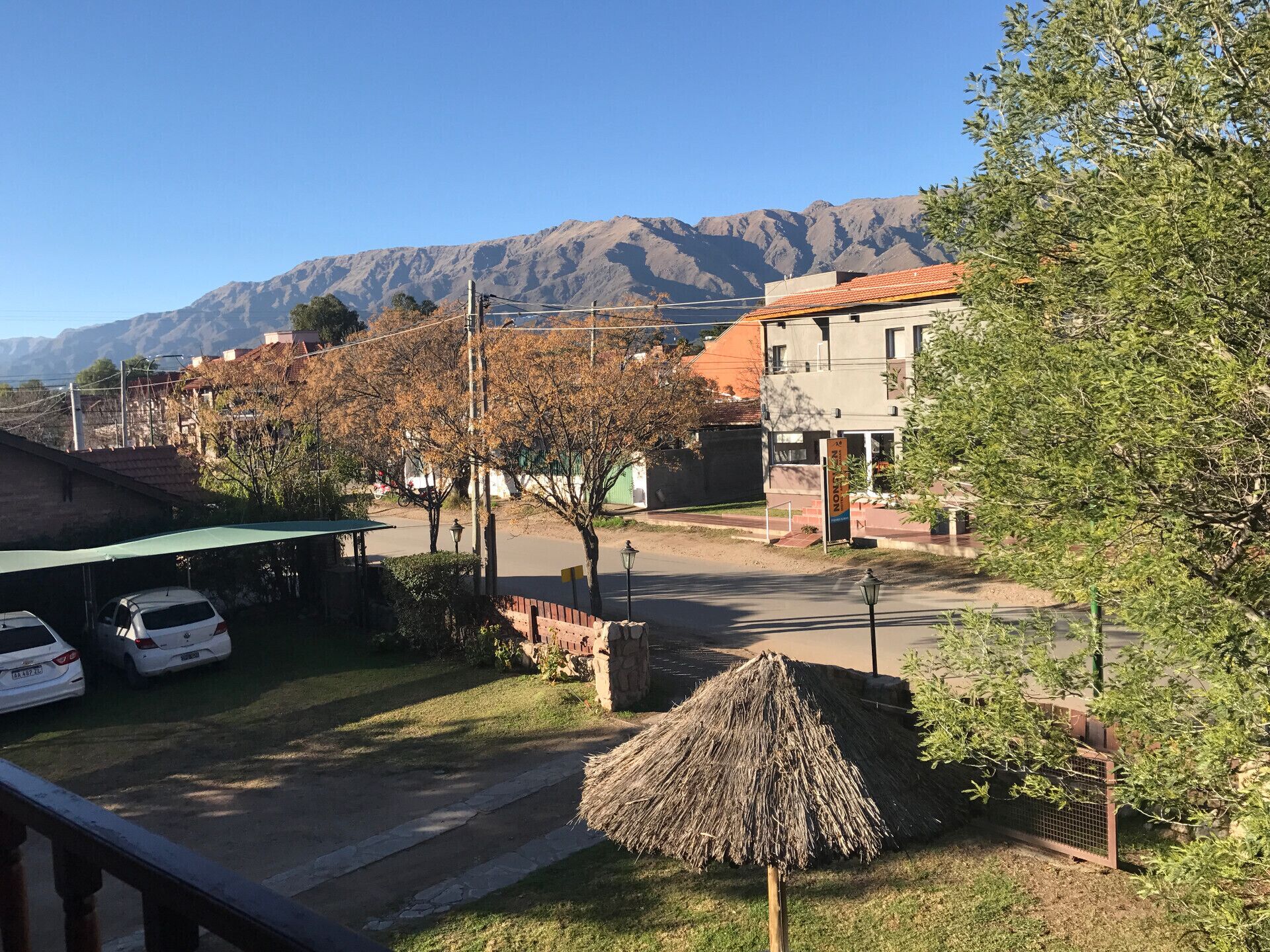 A residential street with houses, a parked car, and a mountain in the background.
