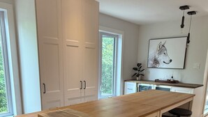 Una cocina con isla de madera, armarios blancos y taburetes negros.