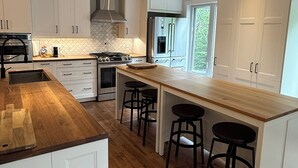 Una cocina moderna con armarios blancos, encimera de madera y una isla central con taburetes de bar.