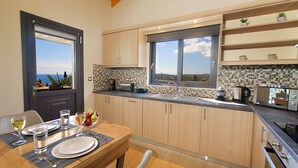 A modern kitchen with wooden cabinets, a large window, and a dining area with a table set for two.