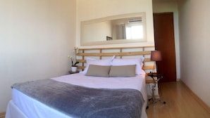 Une chambre à coucher avec un lit, une table de chevet, une lampe et un miroir.