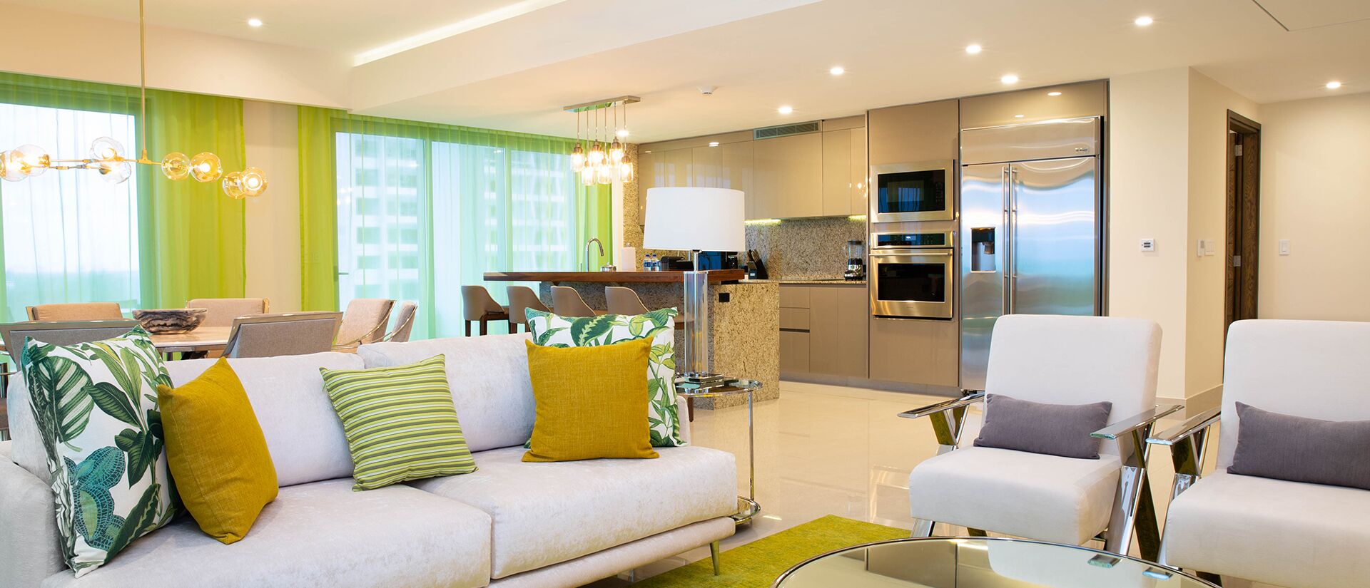 Una sala de estar moderna con sofá, sillones, comedor y cocina equipada.