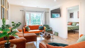 Un salon avec un canapé, des fauteuils, une table basse et un téléviseur.