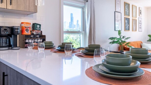 Une cuisine moderne dotée d’un grand îlot central, d’une machine à café et offrant une vue sur la ville.