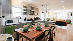 Une cuisine moderne avec un coin repas, un plancher en bois et un canapé vert.