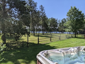 A hot tub in a backyard with a view of a lake and trees.
