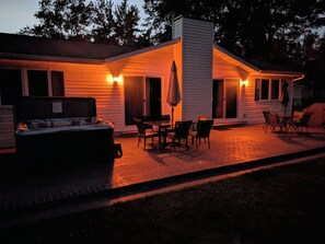 A cozy outdoor patio area with a hot tub, dining table, and chairs.