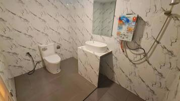 A bathroom with a toilet, sink, and shower.