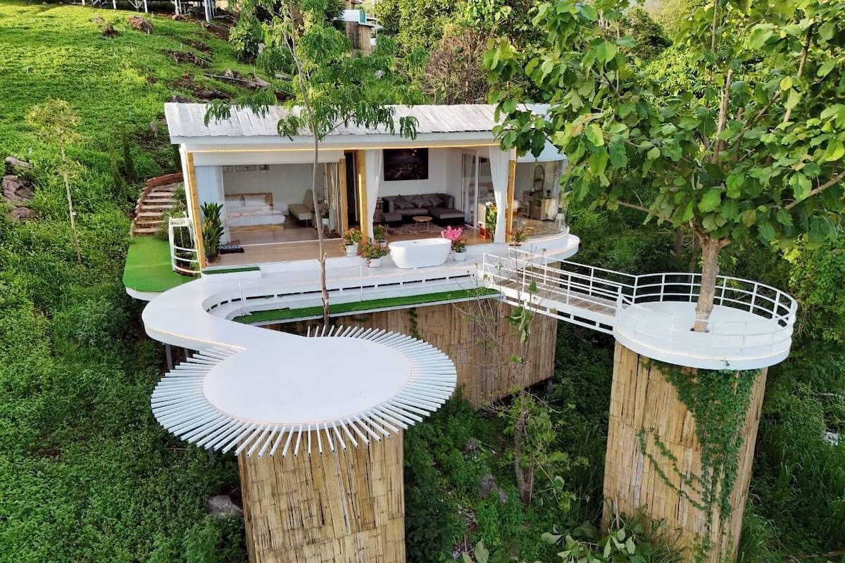 A modern house with a curved deck, a large white bathtub, and a covered outdoor seating area.