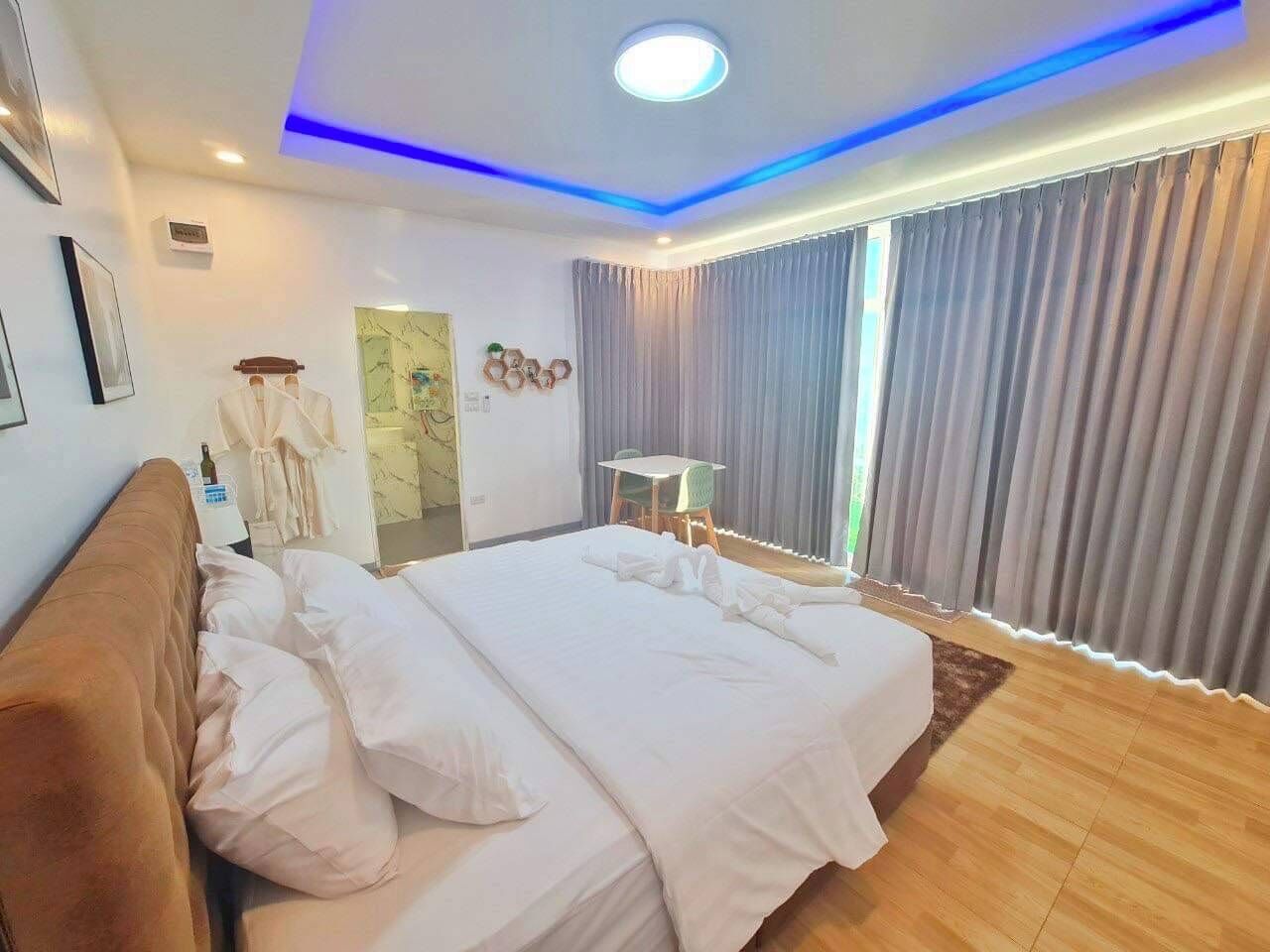 A modern hotel room with a large bed, a desk, and a chair.