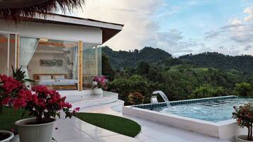 A modern villa with a private pool, a balcony with a sofa and a dining area, and a lush garden.