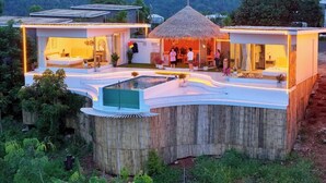 Una casa moderna con una estructura de techo de paja, una piscina y una terraza de madera.