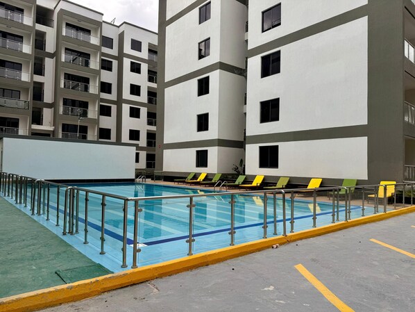 A swimming pool with a metal railing, surrounded by a yellow curb.