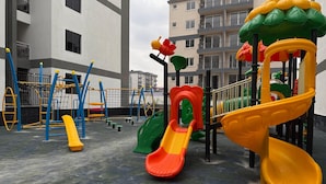 A playground with slides and climbing structures, surrounded by apartment buildings.