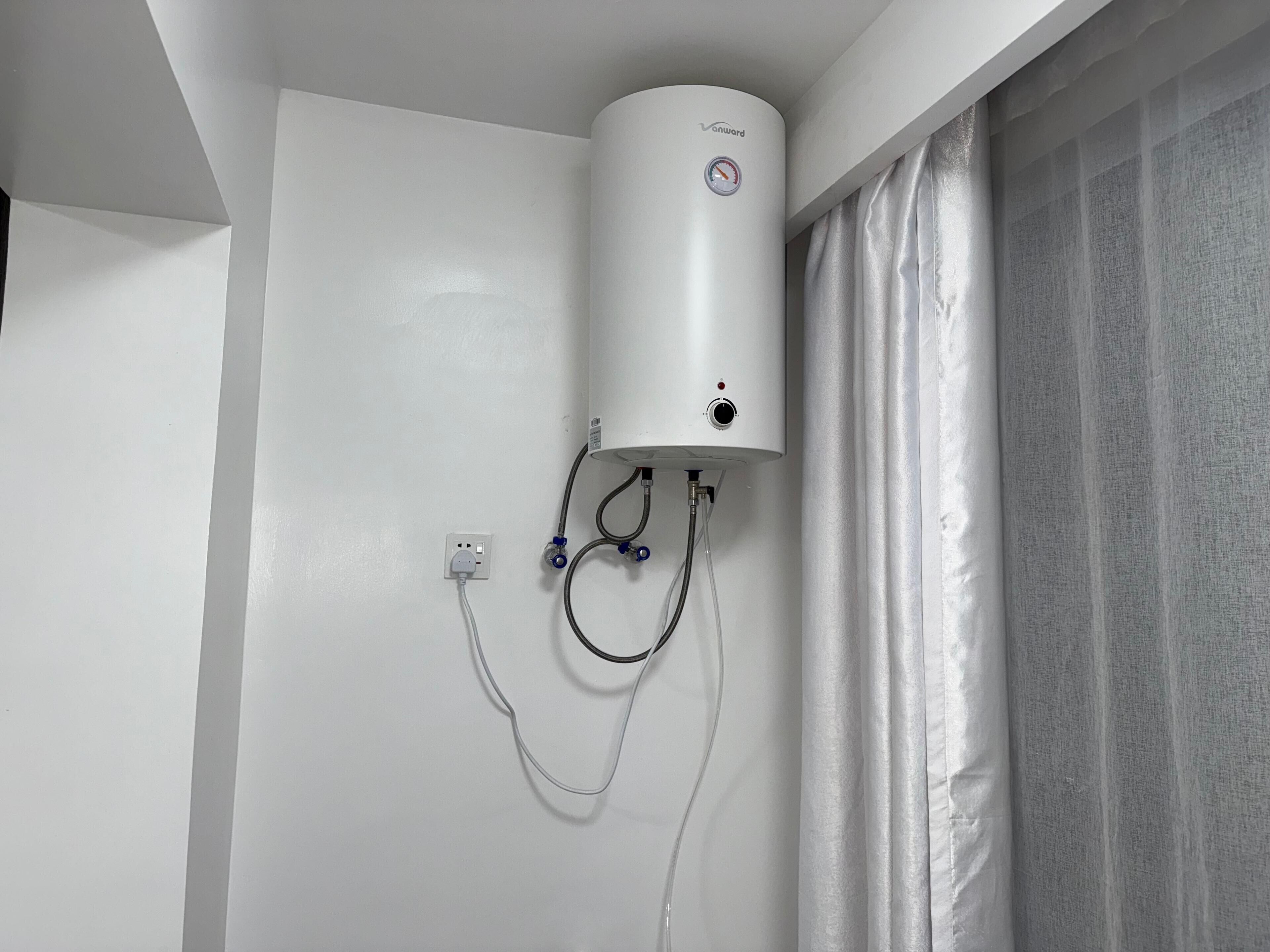 En vandvarmervogn monteret på en hvid væg, med stikkontakt og kontrolpanel nedenunder.