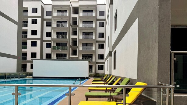 A rooftop pool area with sun loungers and a view of a multi-story building.