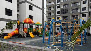 A playground with slides and climbing structures, surrounded by a building with multiple balconies.