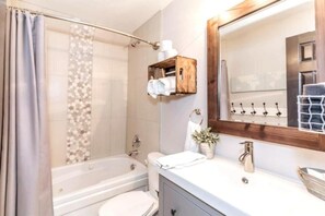 A modern bathroom with a bathtub, toilet, and vanity. - Rustic Loft at Blue (Blue Mountain)