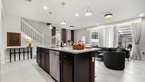 A modern kitchen with a central island, dark cabinetry, and pendant lighting.