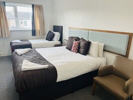 A hotel room with two beds, a sofa, and a window with curtains.