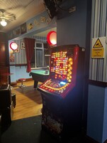 A room with a pool table, a pinball machine, and a caution sign indicating CCTV operation.