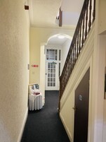 A hotel hallway with a fire exit door, a no smoking sign, and a table with brochures.