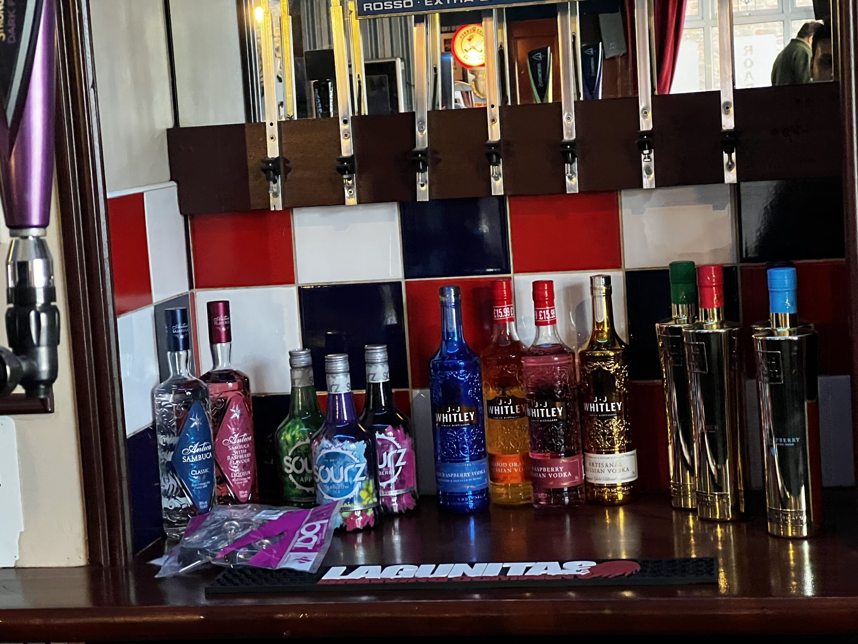Een barruimte met verschillende drankflessen en een bord waarop 'LAGUNITAS' staat.
