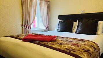 A hotel room with a bed, striped curtains, a headboard, and a window.