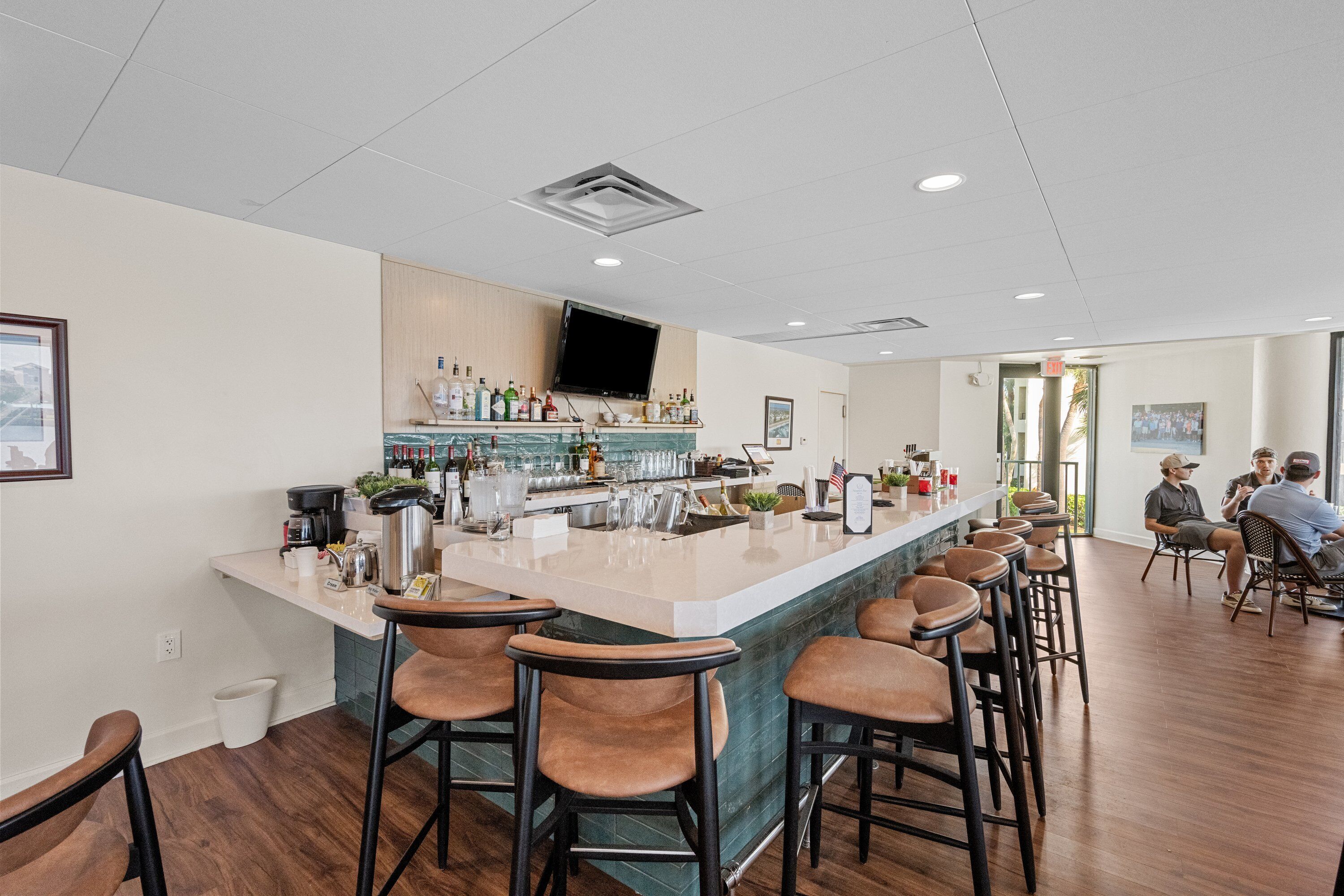 Une cuisine moderne dotée d’un coin bar, de tabourets de bar en bois et d’un téléviseur à écran plat fixé au-dessus du bar.