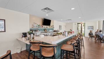 Une cuisine moderne dotée d’un coin bar, de tabourets de bar en bois et d’un téléviseur à écran plat fixé au-dessus du bar.