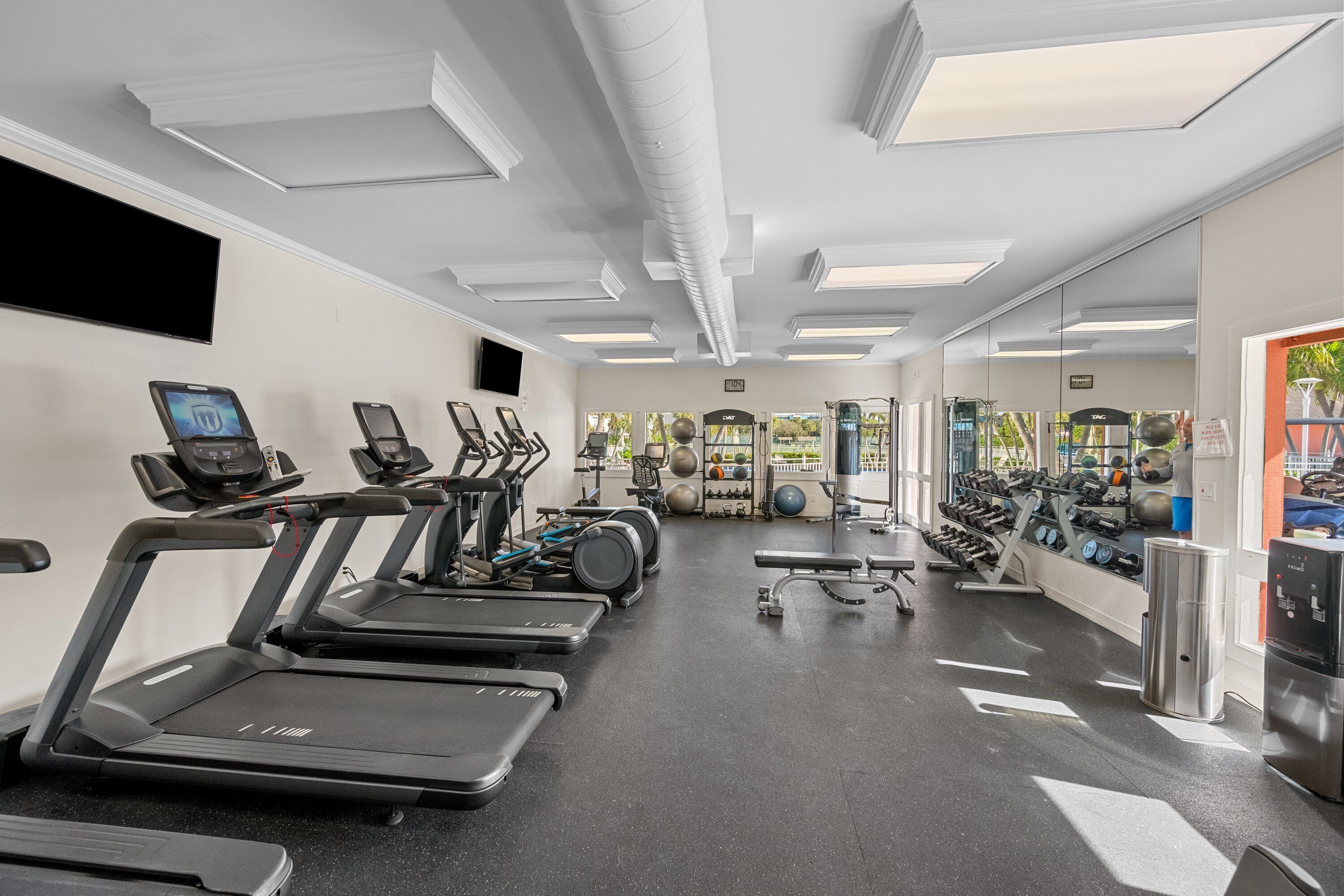 Une salle de sport équipée de tapis de course, de vélos d’appartement et de divers appareils d’exercice.