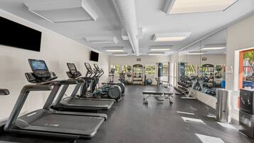 Une salle de sport équipée de tapis de course, de vélos d’appartement et de divers appareils d’exercice.
