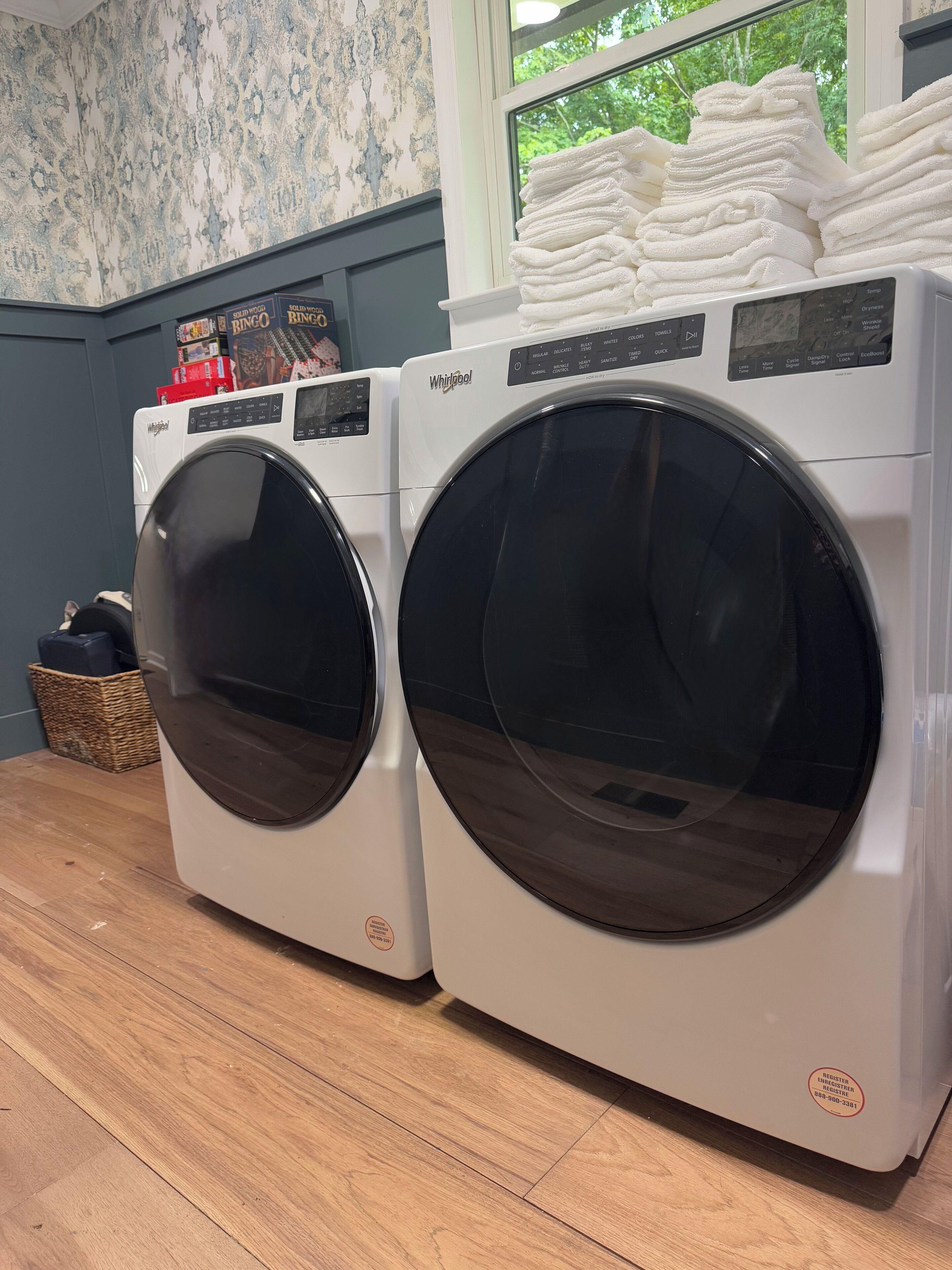 Two front-loading Whirlpool washing machines in a laundry room with a window view.